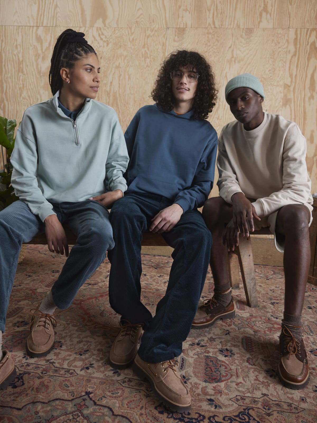 Offizielles Stanley/Stella-Kampagnenfoto der AW22 Dry-Kollektion: drei Models in gedeckten Pastelltönen (mint, blau, beige) sitzen auf einer Bank